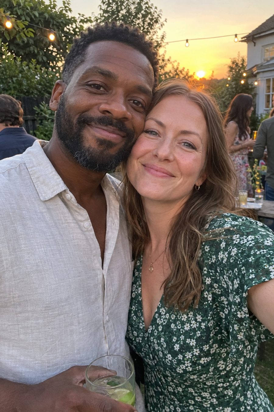 Smiling couple cheek to cheek at a garden party at sunset